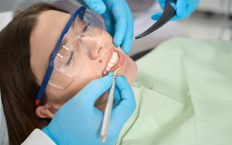 female client protective eyewear lying supine while professional dentist removing