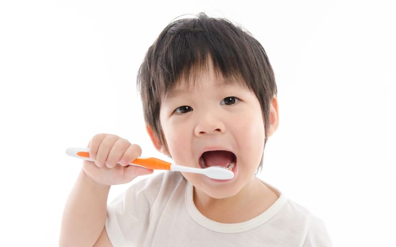 cute asian bay brushing teeth on white background