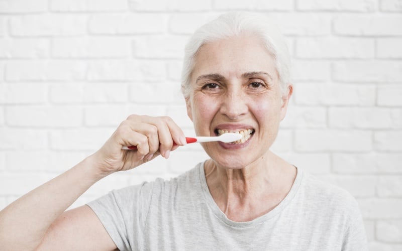 elder woman washing her teeth